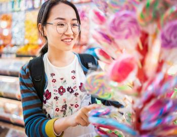 Young Girl Choosing A Lollipop In Candy Store - Bullfrog Corner