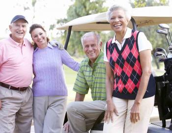 Friends leaning against a golf cart smiling and laughing