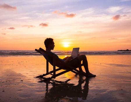 Man sitting on the beach with his computer