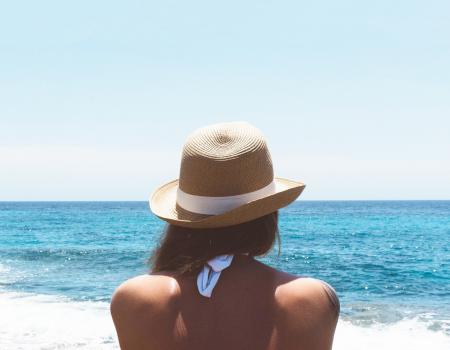 Girl in a sunhat looking out at the beach