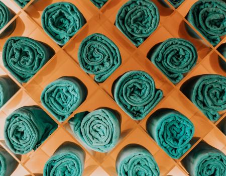 Green linen beach towels rolled up in a modern orange holder