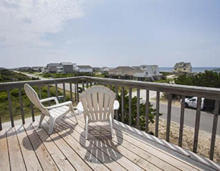 Beach chairs on a front porch looking towards the ocean