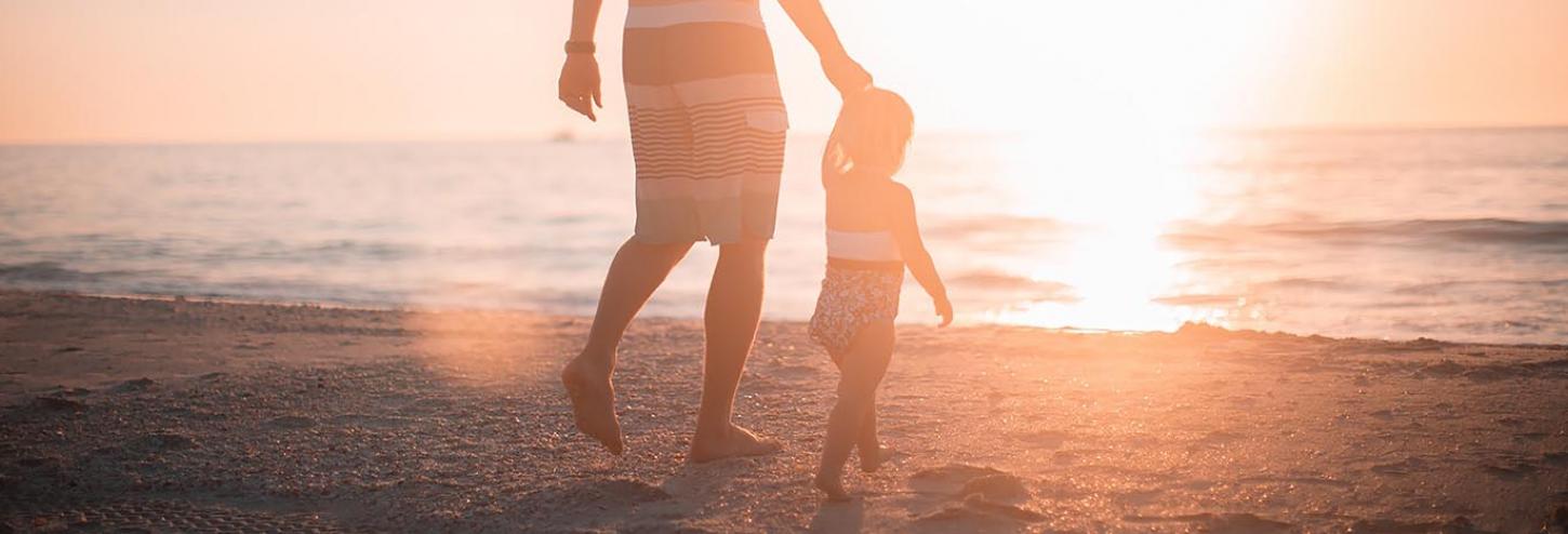 Dad and daughter holding hands on the beach at Caswell Beach, NC