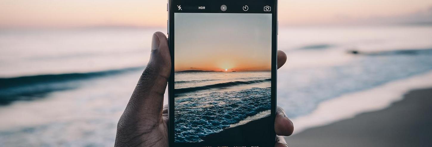 The sun setting on the beach viewed through a phone