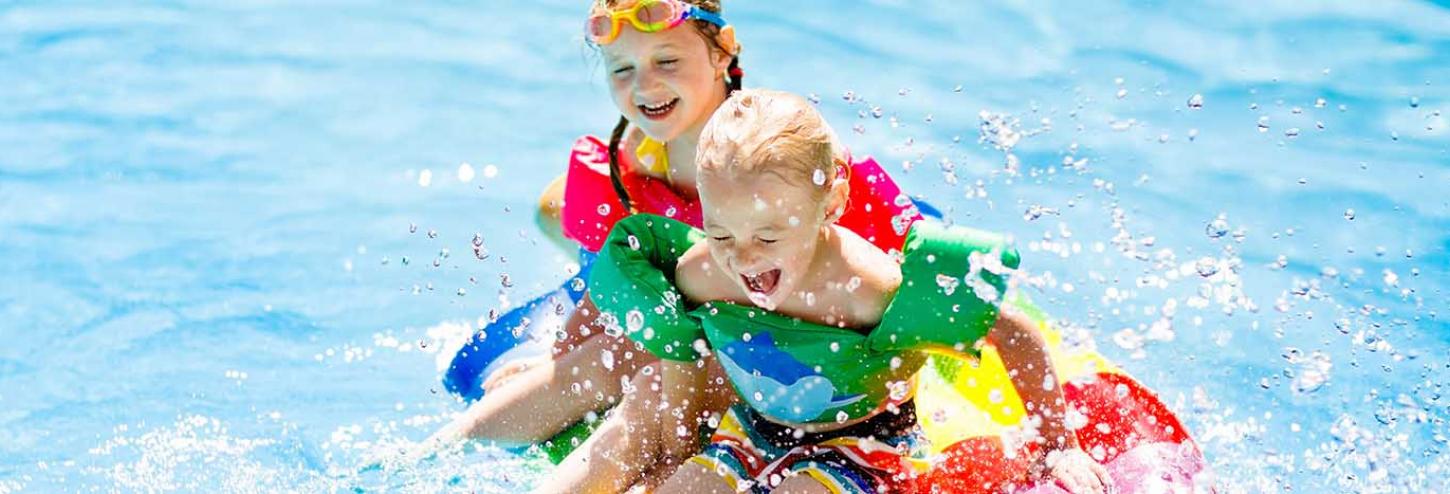 Kids swimming in a community pool with floaties