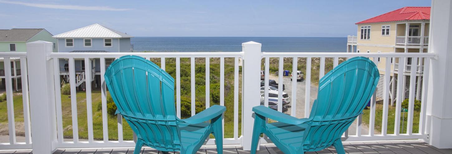 Beach chairs on a front porch looking towards the ocean