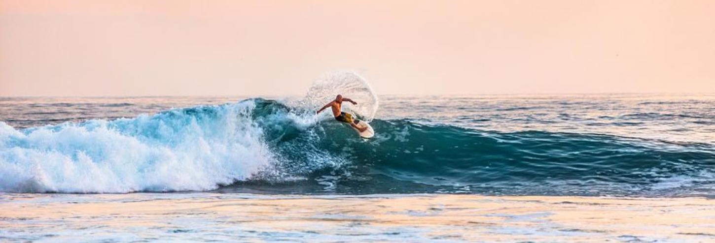 Surfer in North Carolina with a light pink sunset