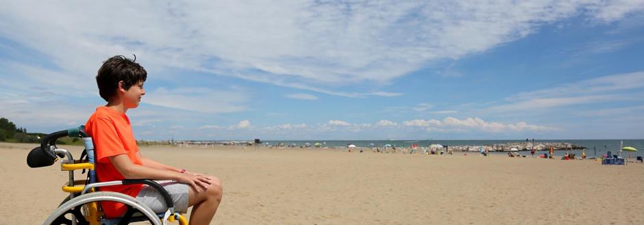 Young boy in a beach wheelchair enjoying Oak Island