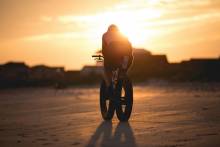 Man biking on Oak Island Beach during sunset