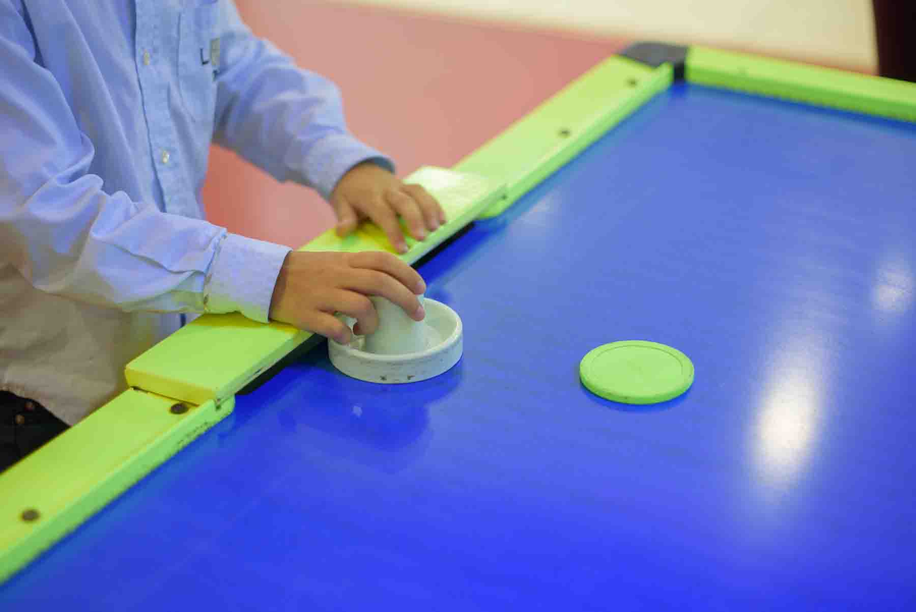 Little kid playing air hockey