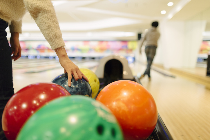 A woman picks up a bowling ball