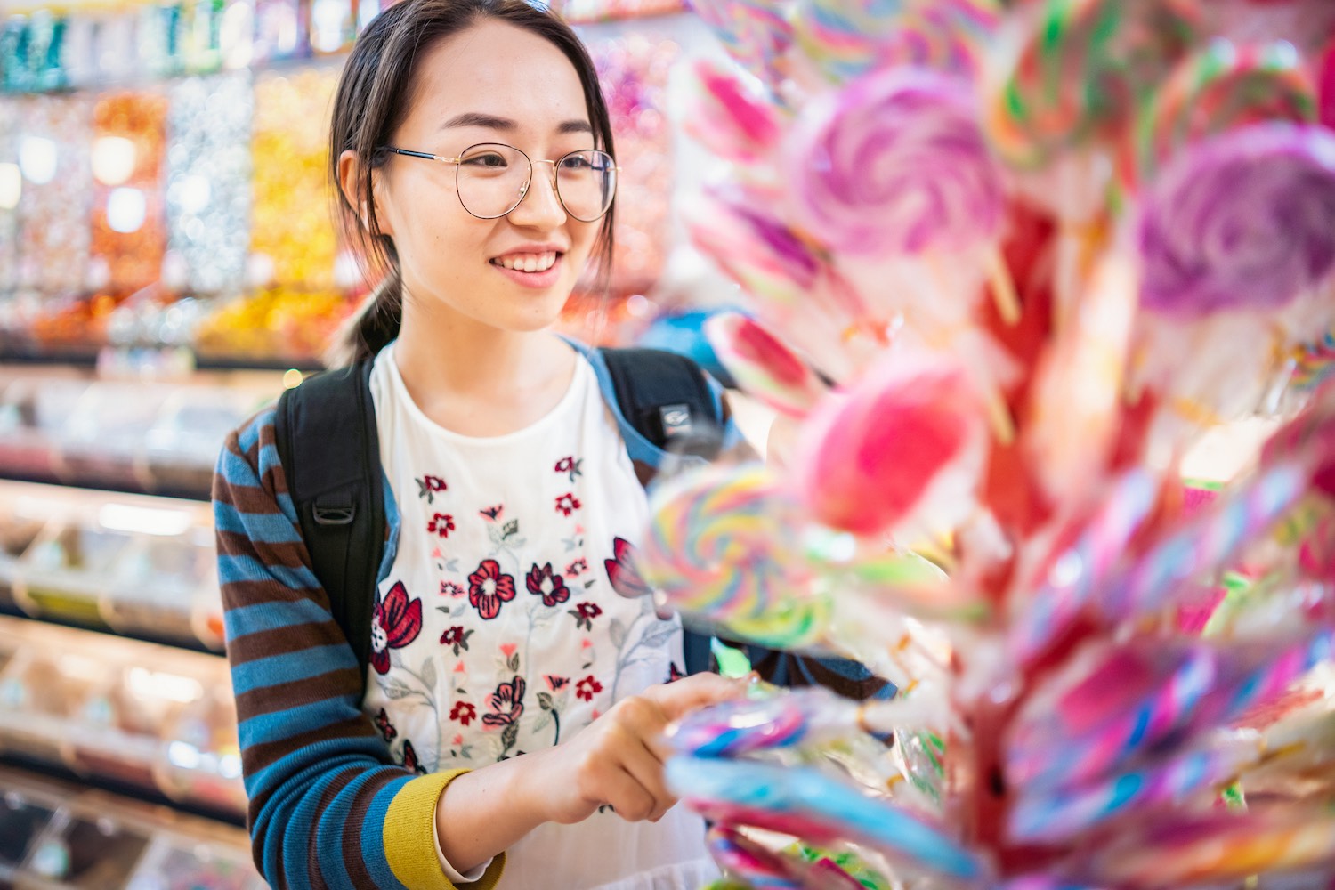 Young Girl Choosing A Lollipop In Candy Store - Bullfrog Corner