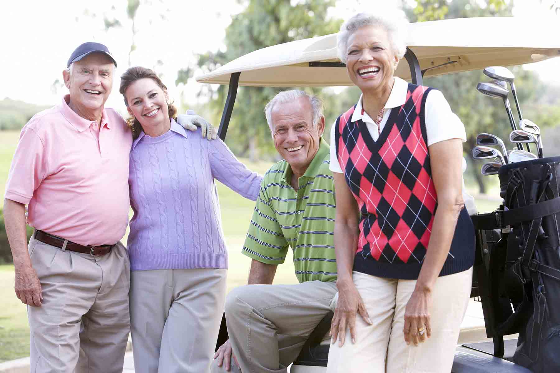 Friends leaning against a golf cart smiling and laughing