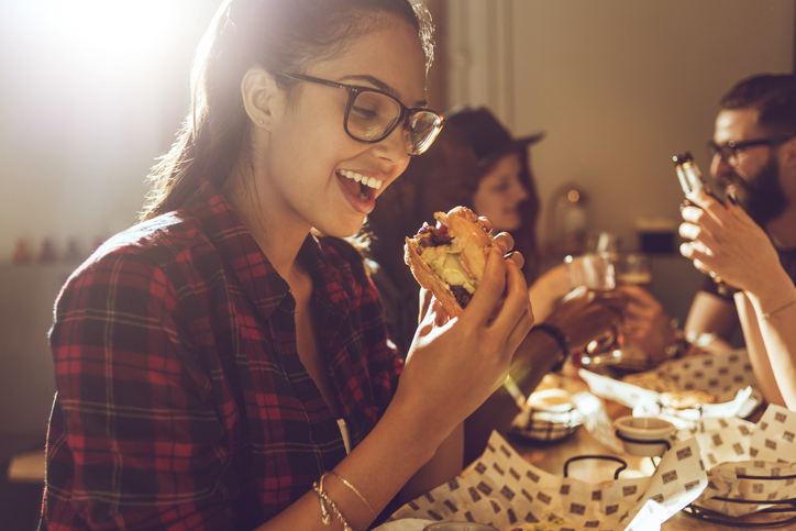 girl in glasses eating a cheeseburger