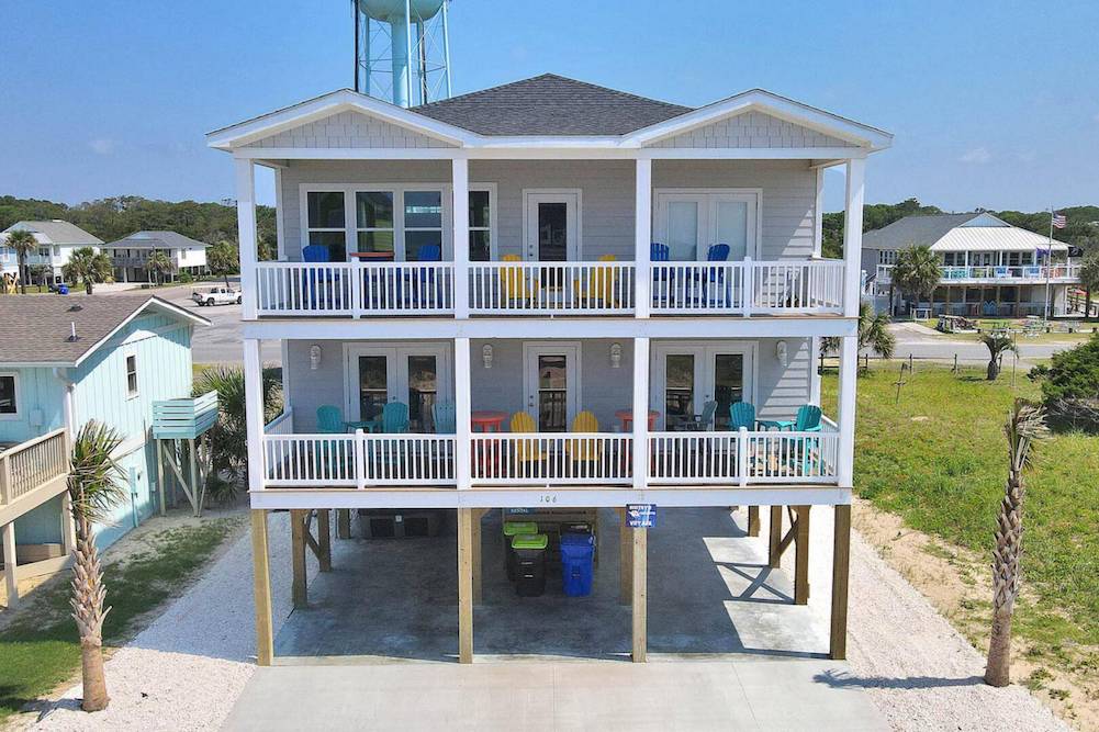 Front of beach vacation home showing 2 balconies with multicolored beach chairs