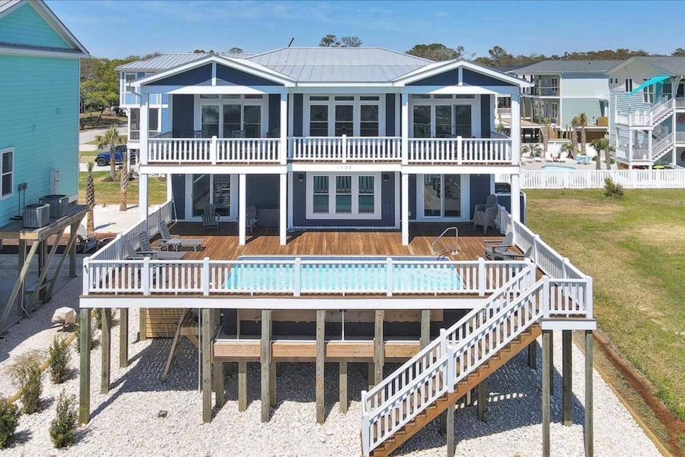 back view of beach house featuring in-ground pool