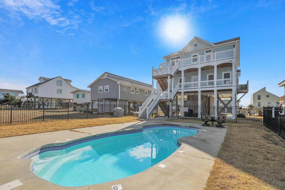 back view of beach house featuring in-ground pool