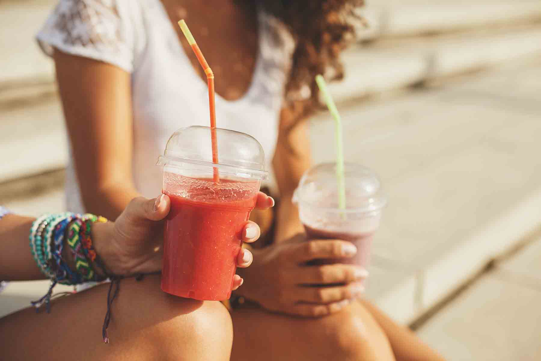 Two girl friends enjoying fresh smoothies together
